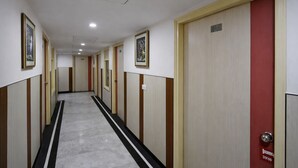 A hallway with doors on both sides, some with red frames, and others with beige frames. - KDSON Vindhya Inn (New Delhi)