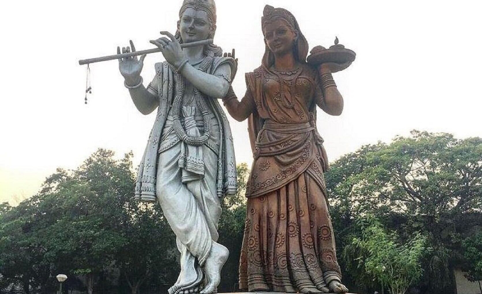 A statue of a male figure playing a flute and a female figure carrying a pot.