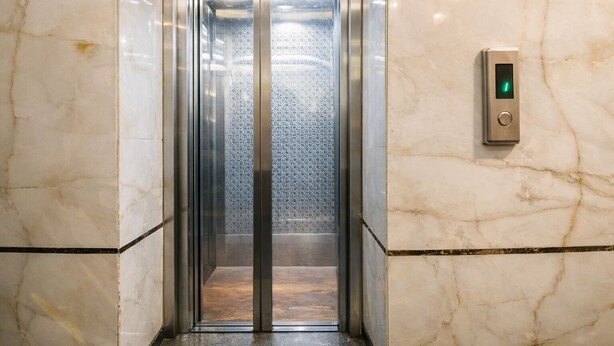 An elevator with a metallic interior and a glass door, featuring a control panel with a green light. - KDSON Vindhya Inn (New Delhi)