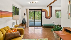 Una sala de estar moderna con un sofá, un banco, una mesa y un ventanal grande.