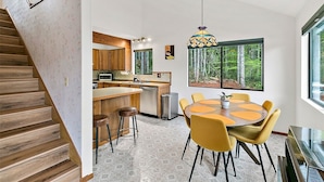 Una cocina moderna con armarios de madera, una isla grande y un comedor con sillas amarillas.