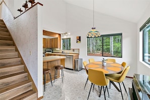 Una cocina moderna con armarios de madera, una isla grande y un comedor con sillas amarillas.