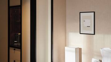 Une chambre d’hôtel avec un lit, une table de chevet avec une lampe, un tableau encadré au mur et une armoire en bois.