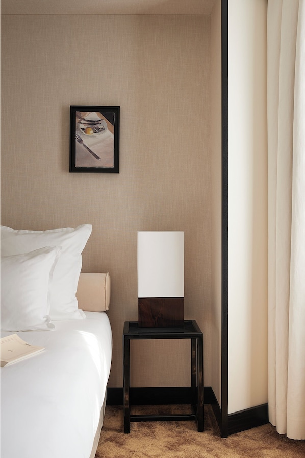A hotel room with a bed, a nightstand, a framed picture on the wall, and a window with curtains. - Hôtel Atlas (Paris)