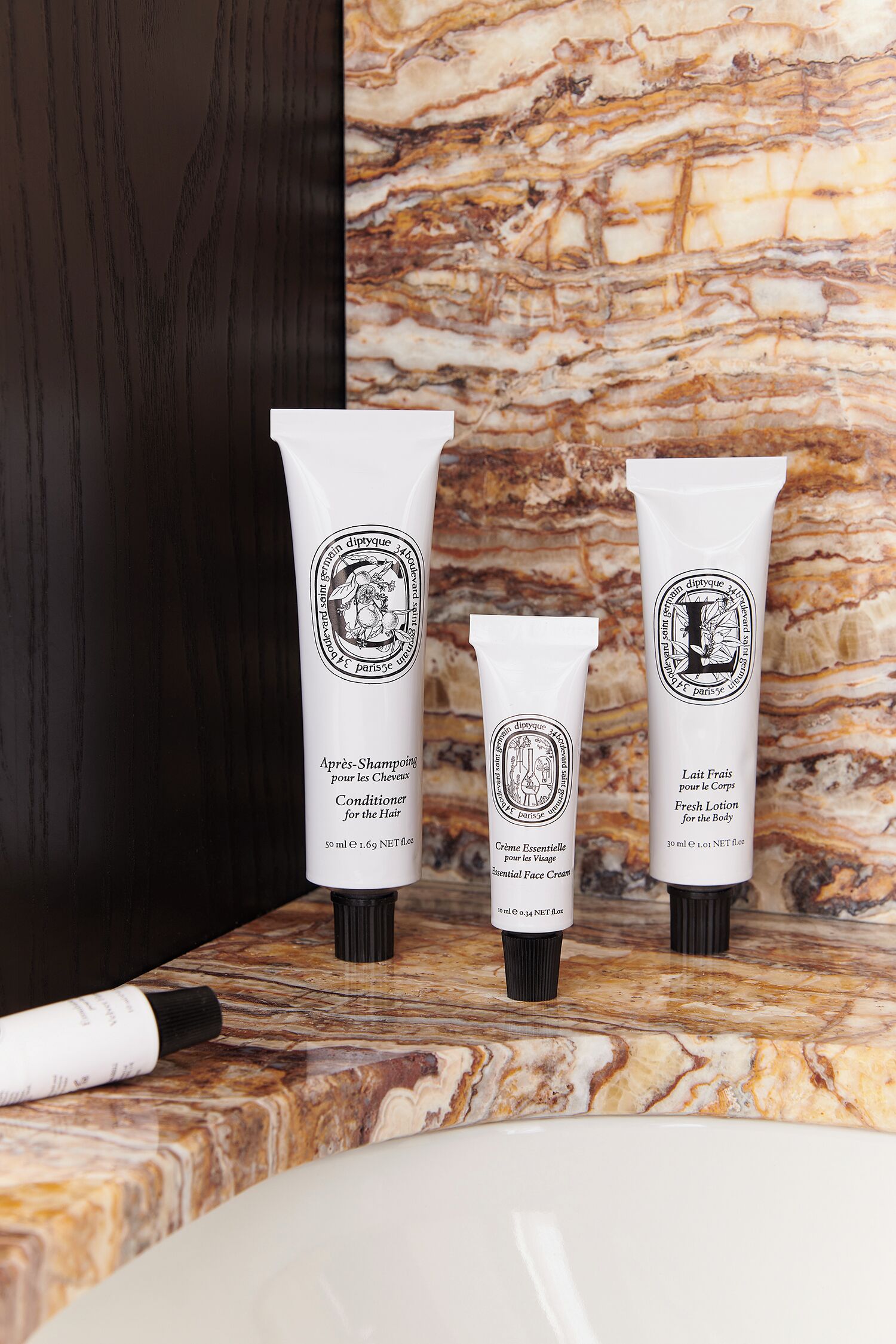Trois tubes de produits de toilette sur un comptoir en marbre.