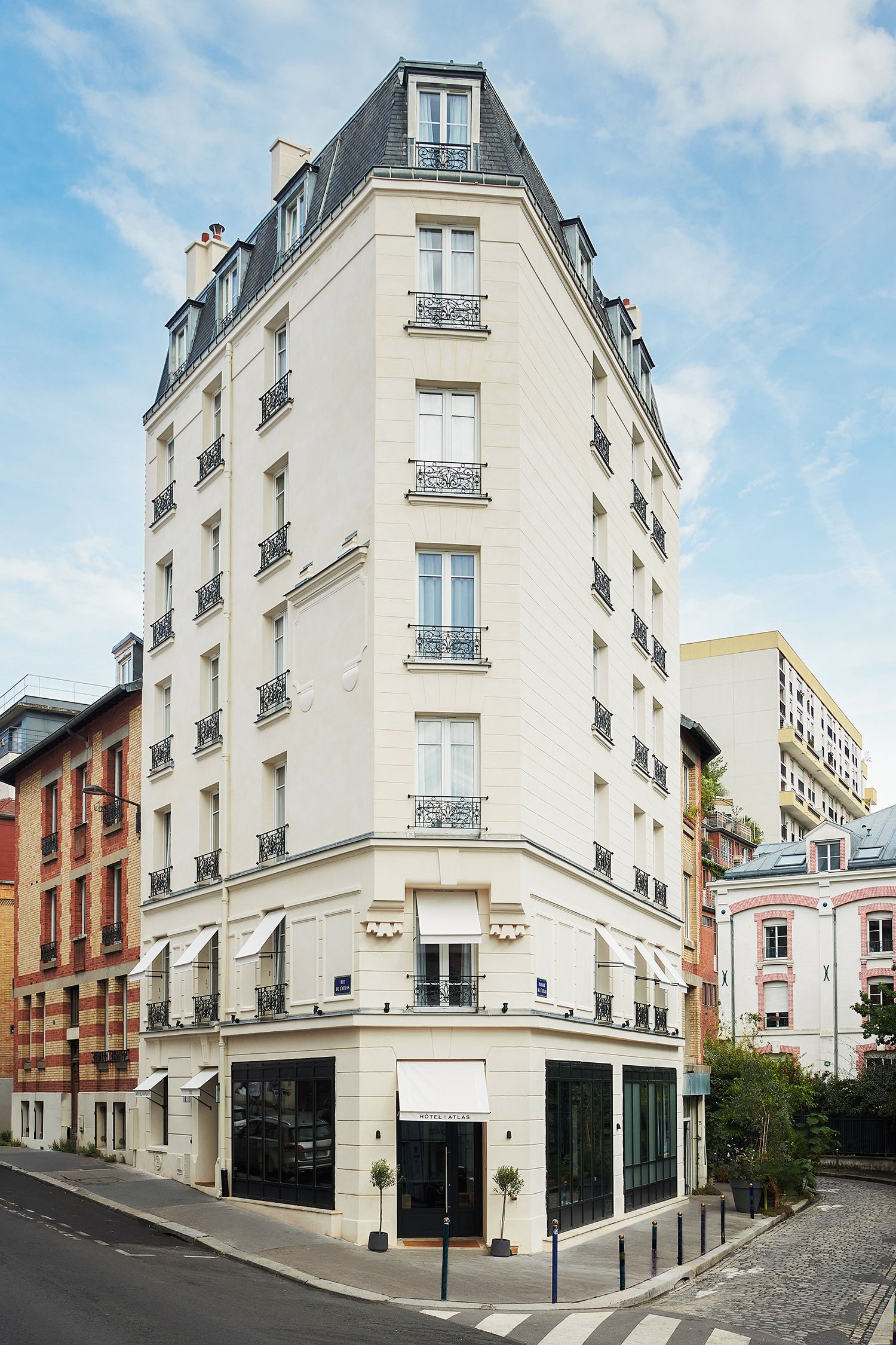 Un hotel de varios pisos con entrada en esquina, ventanas grandes y balcones.