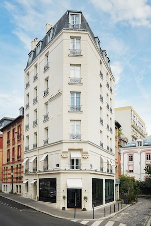 A multi-story hotel with a corner entrance, large windows, and balconies. - Hôtel Atlas (Paris)