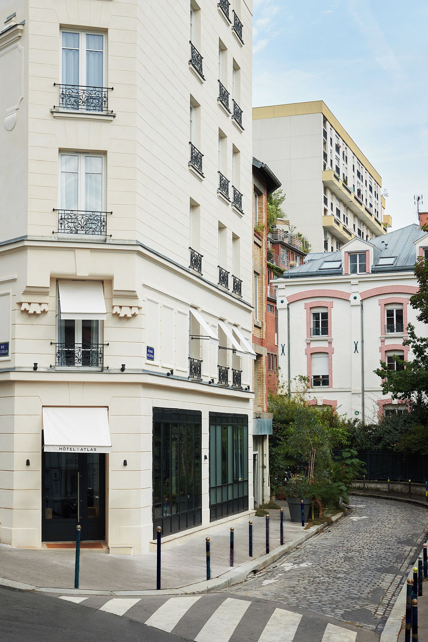 Un hotel con fachada blanca, varios balcones y una calle adoquinada en primer plano.