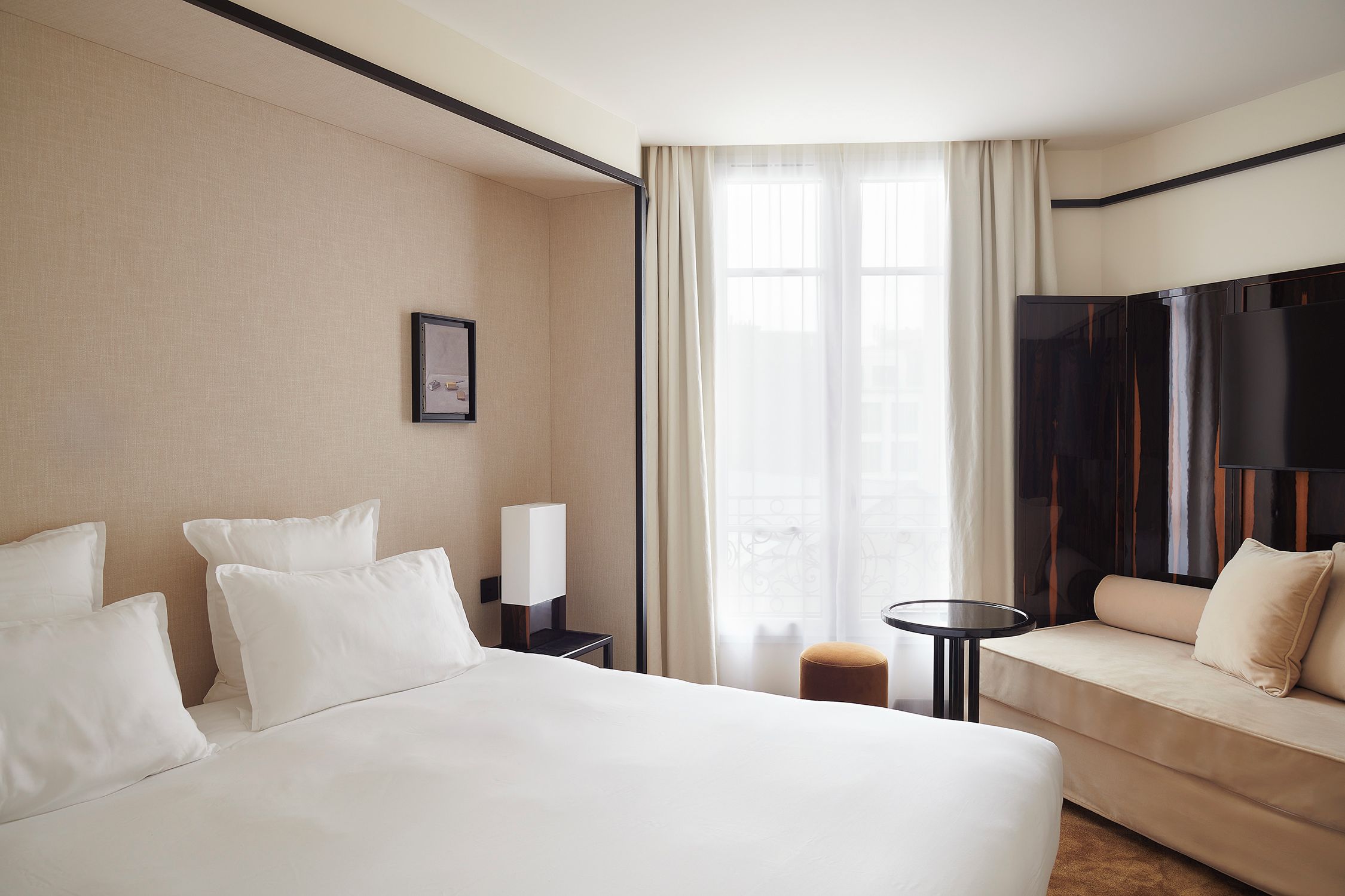A hotel room with a bed, a sofa, a small table, and a TV.