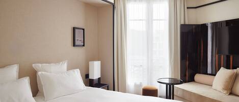 A hotel room with a bed, a sofa, a small table, and a TV.