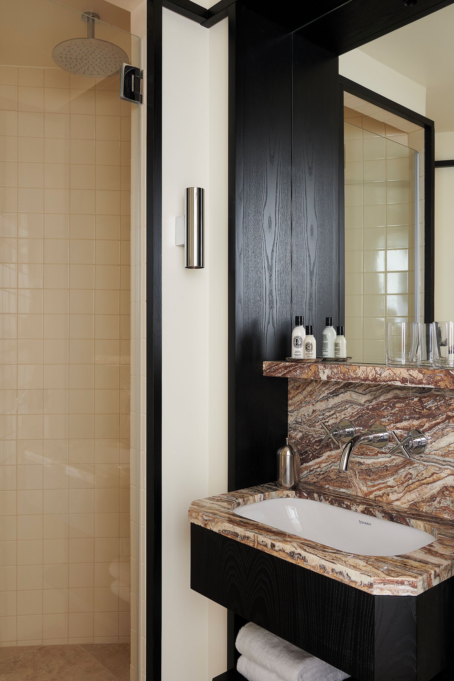 A bathroom with a shower, a sink with a marble countertop, and a mirror.