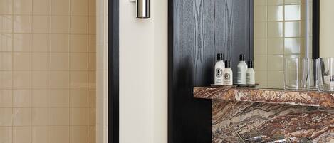 A bathroom with a shower, a sink with a marble countertop, and a mirror.