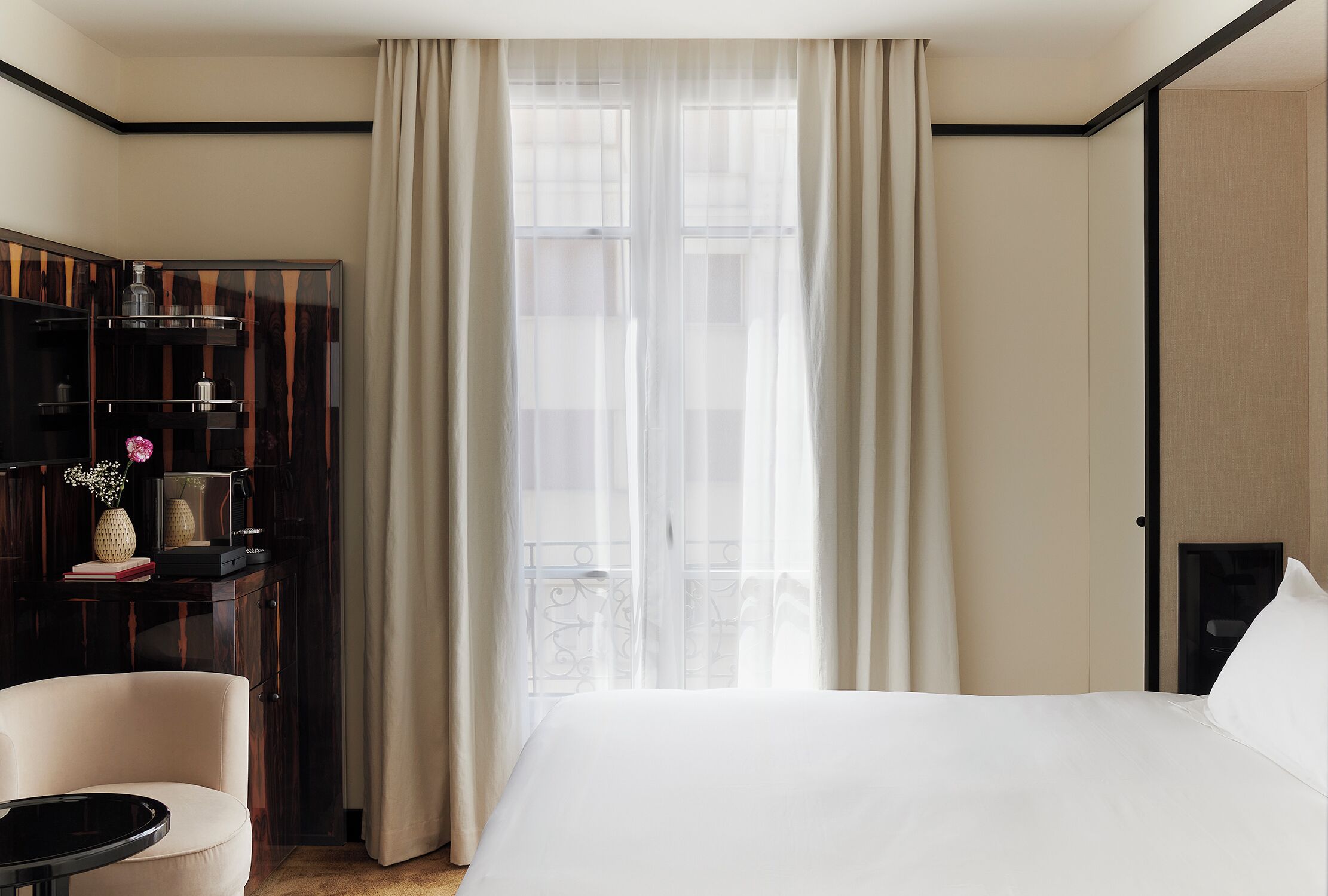 Une chambre d’hôtel comprenant un lit, un bureau avec une chaise, une armoire et une fenêtre avec des rideaux.