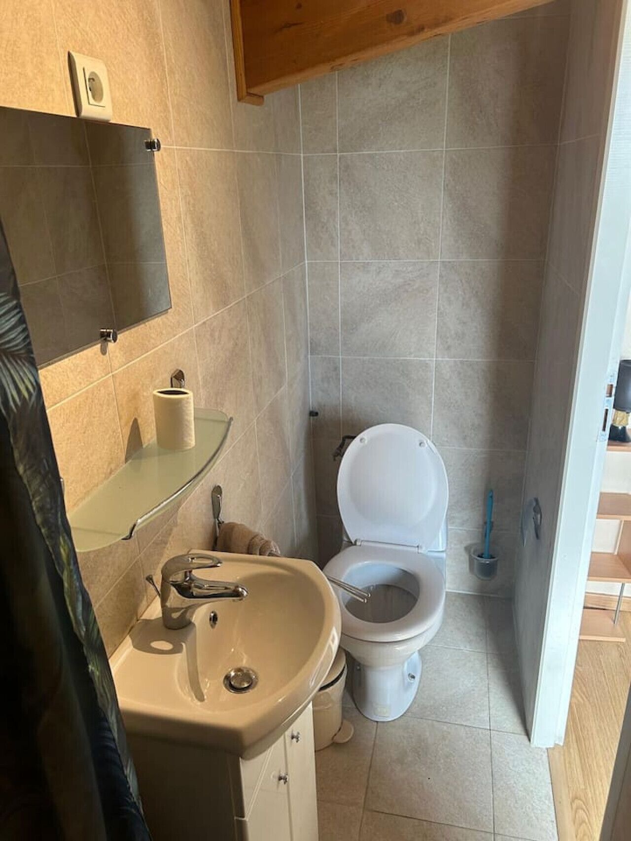 A small bathroom with a toilet, sink, and mirror.