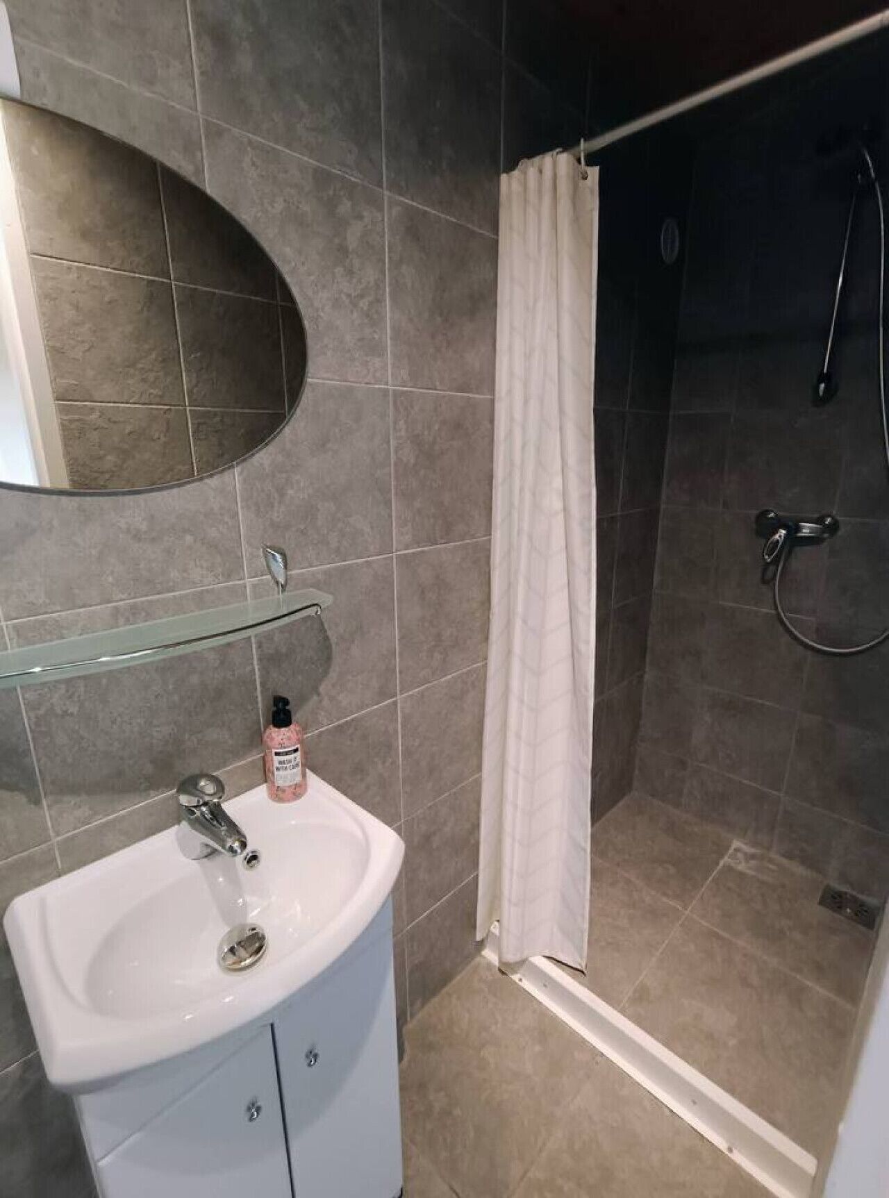 A bathroom with a white sink, a mirror, and a shower area with a curtain.