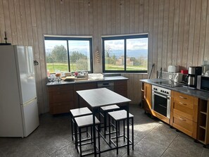 Eine Küche mit Holzschränken, einem weißen Kühlschrank, einem Herd und einem Essbereich mit Tisch und Hockern.