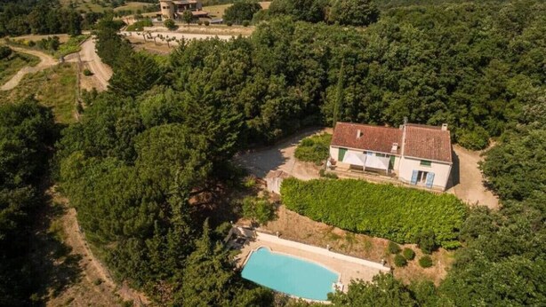 Vista aèria d'una casa envoltada de vegetació abundant, amb una piscina i un viñedo a prop.