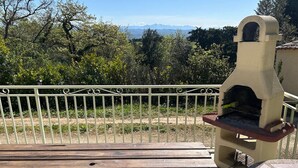 Terrassa a l'aire lliure amb taula de pedra i una graella de forlla de maó.