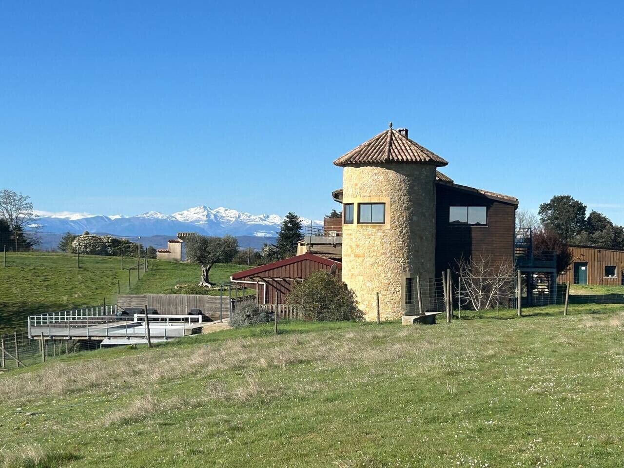 Ein Steinturm mit flachem Dach, umgeben von einem eingezäunten Bereich mit einer Holzterrasse.