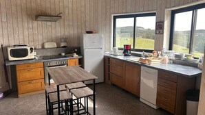 Eine kompakte Küche mit Holzausstattung, einer Mikrowelle, einem Kühlschrank, einem Spülbecken und einem Fenster mit Blick ins Grüne.