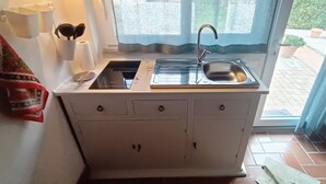 Una cocina compacta con lavamanos, estufa y armarios.