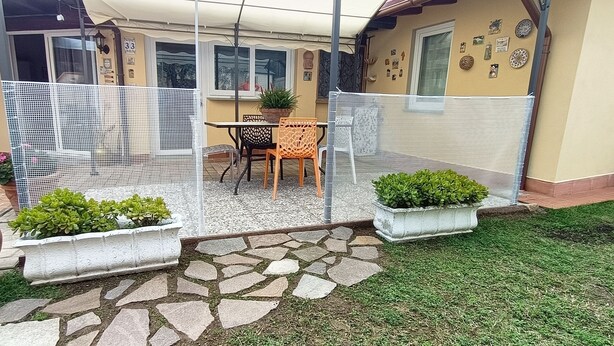 Un patio con un camino de piedra, mobiliario exterior y plantas en macetas.