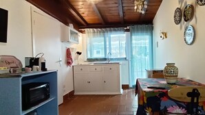 Una cocina con microondas, un lavabo y una mesa con un florero.