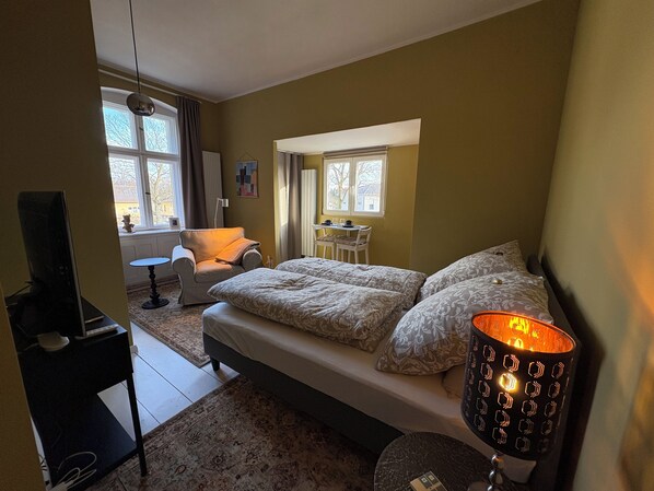 Une chambre à coucher avec un lit, un bureau, une chaise et une lampe.