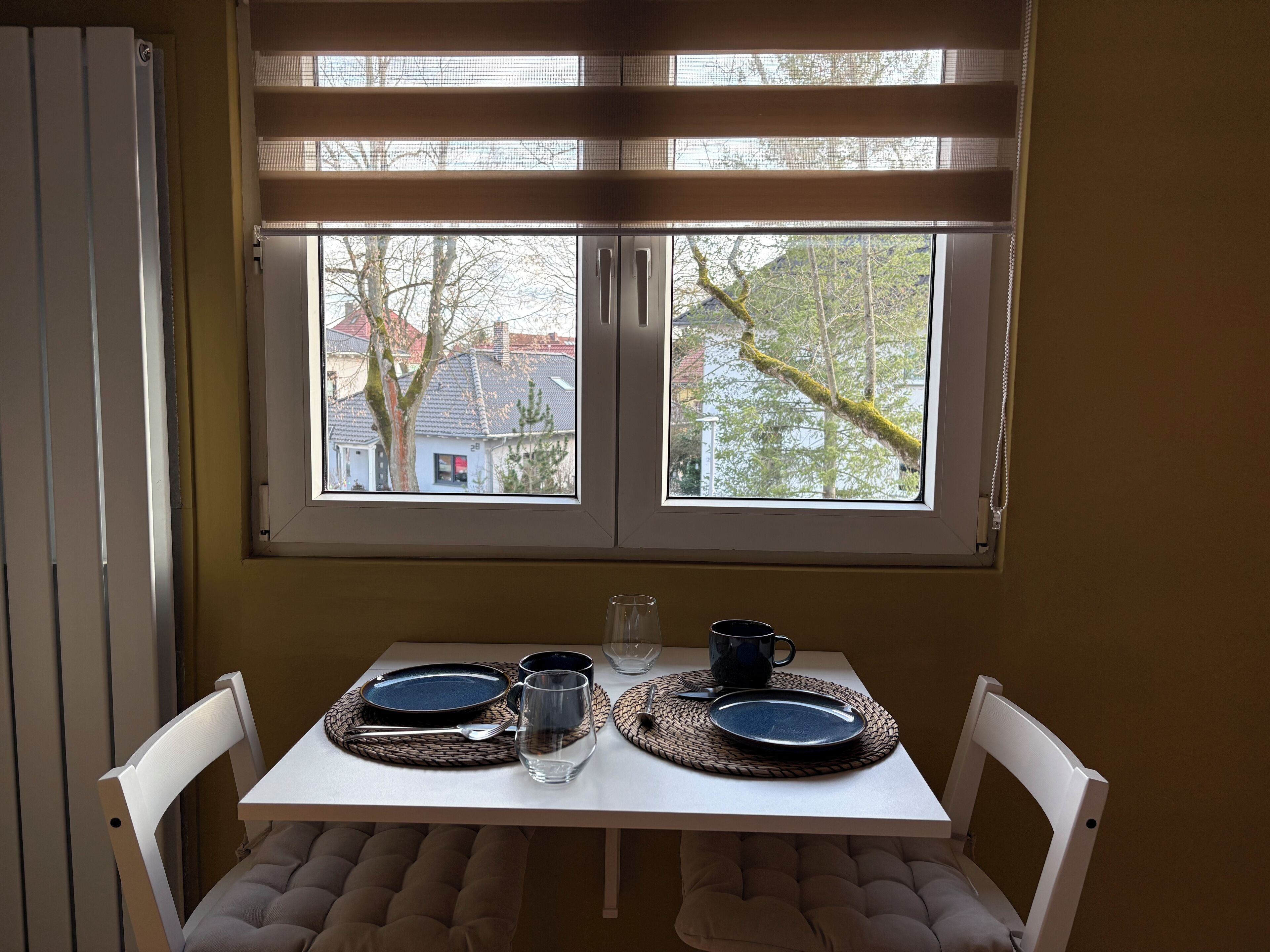 Ein Esstisch mit zwei Tellern, zwei Gläsern und einer Tasse, gedeckt für zwei Personen.