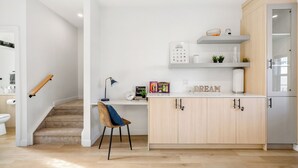 A modern kitchen with wooden cabinets, a white countertop, and a built-in coffee machine. - New 1500 ft² Home w/ AC & Garage | 7 mins to DT (Calgary)