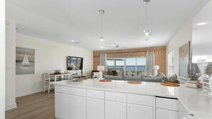Uma cozinha moderna com uma ilha grande, detalhes em madeira e vista para o oceano.