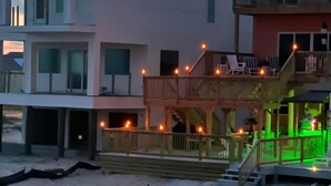 Um imóvel à beira-mar com vários edifícios, incluindo uma casa de dois andares com varanda e um espaço deck com luzes de corda.