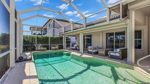 Ein überdachter Patio mit Sitzgelegenheiten umgibt einen Indoor-Pool mit klarem Wasser und Blick ins Freie.