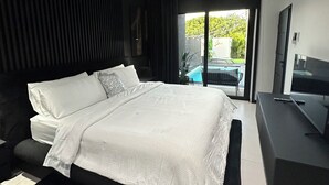 Ein modernes Schlafzimmer mit einem großen Bett, einem Flachbildfernseher und einer Glastür zum Balkon.
