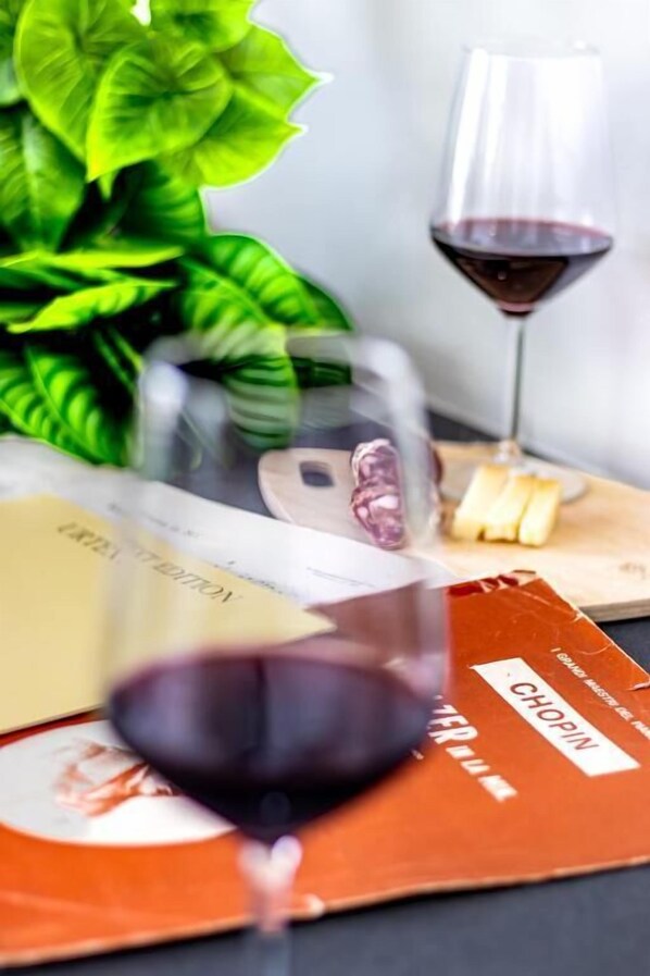 A glass of red wine, a book, and a plant on a table. - Il Panoramico Rooms (Cagliari)