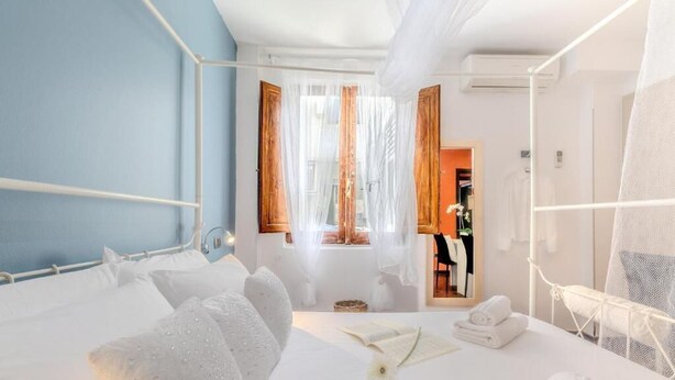 Een hotelkamer met een bed, een raam met gordijnen, een spiegel en een klein tafeltje met handdoeken.