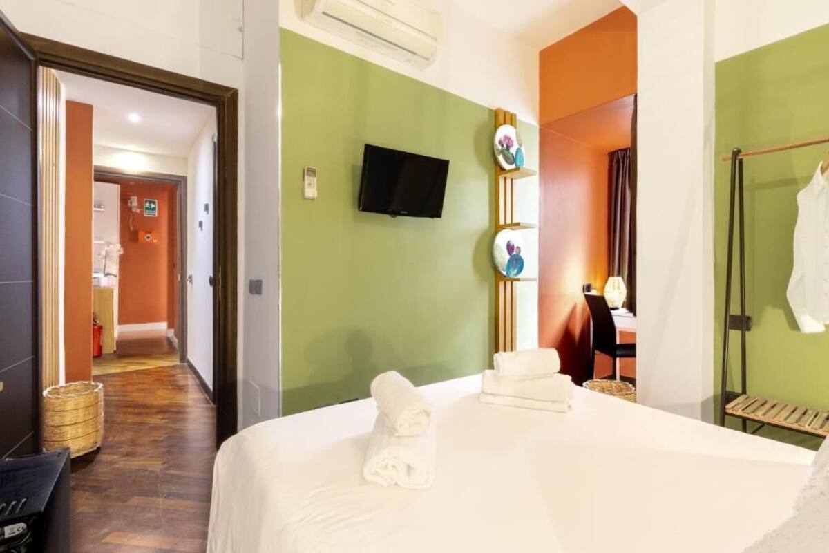 Une chambre d’hôtel avec un lit, une télévision, une petite table et une chaise.