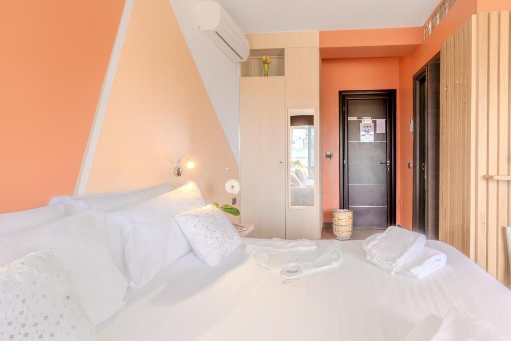 A hotel room with a bed, a wardrobe, a mirror, and a door.
