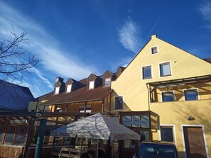 Straßenansicht mit Gebäuden, darunter ein gelbes Gebäude mit einem Schild, auf dem 'Gasthof Altler Wirt' steht.