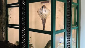 Una habitación con ventana de marco verde, una lámpara decorativa colgante y un ventilador de techo.
