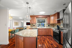 Eine moderne Küche mit Holzschränken, Granit Arbeitsplatten und Edelstahlgeräten, inklusive einer integrierten Kücheninsel.