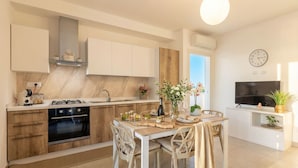 Eine moderne Küche mit weißen Schränken, einem eingebauten Backofen und einem Essbereich mit Tisch und Stühlen.
