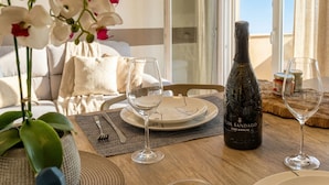 Et spisebord med en flaske Col Sandago vin, to vinglas og en tallerken med tegning.