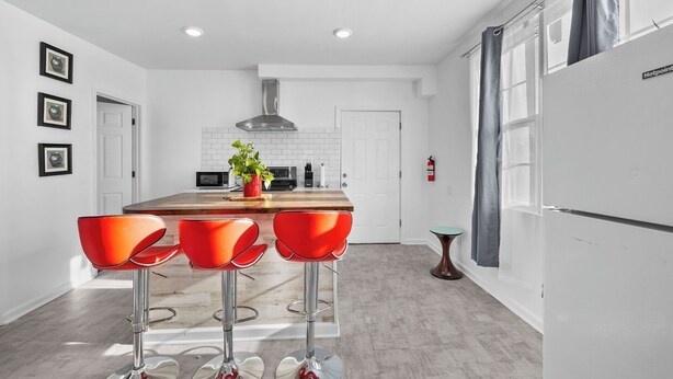 A modern kitchen with a central island, bar stools, a microwave, and a stainless steel range hood. - Charming 3-bedroom Home in Southwest Detroit (Detroit)
