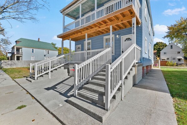 A two-story building with a wooden deck and a staircase leading to the upper floor. - Charming 3-bedroom Home in Southwest Detroit (Detroit)