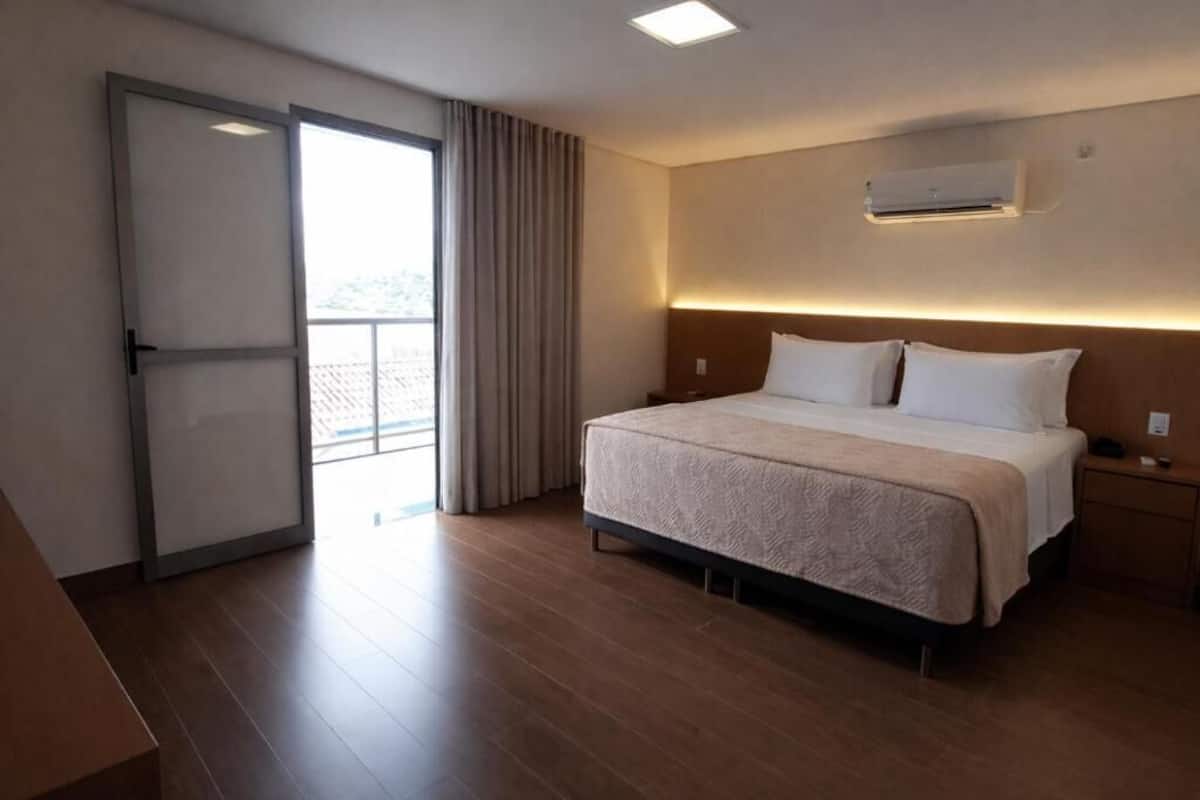 Une chambre d’hôtel comprenant un lit, une table de chevet, un appareil de climatisation, une porte-fenêtre coulissante et une vue sur l’extérieur.