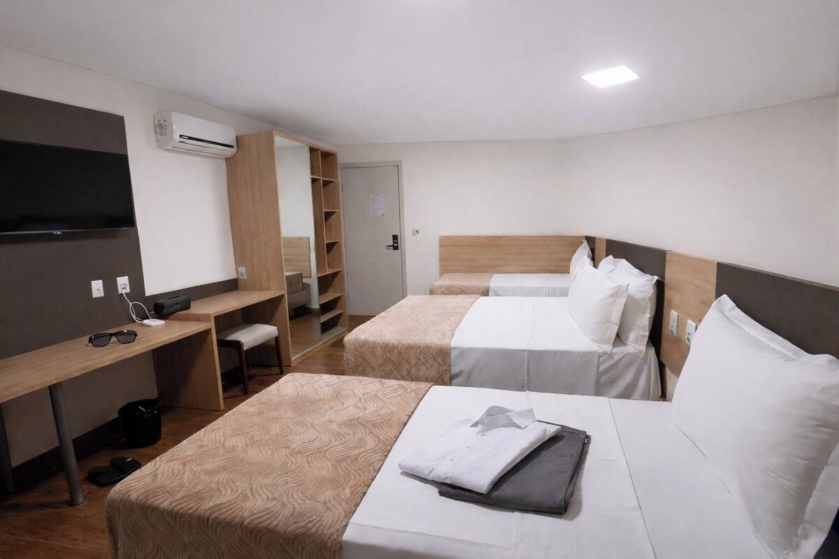 Une chambre d’hôtel avec deux lits, un bureau, une chaise et une télévision.
