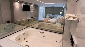 A modern bathroom with a large bathtub, a glass-enclosed vanity, and a mirror. - HOTEL OURO MEL (Santa Bárbara)