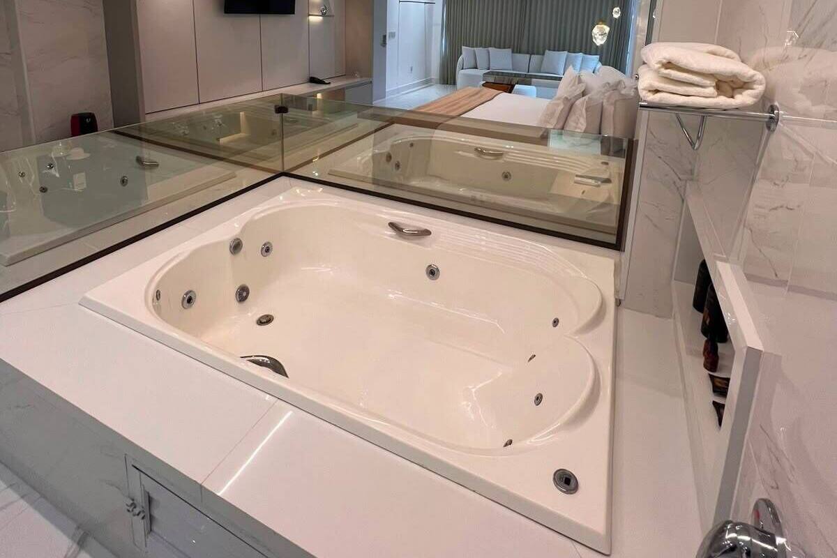 Une salle de bain moderne avec une grande baignoire, un meuble-lavabo avec un encadrement en verre et un miroir.