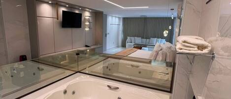 Un bagno moderno con una vasca da bagno ampia, un mobile lavabo con ante in vetro e uno specchio.